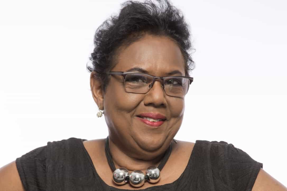 Theresa Awai, a woman with short dark hair, wearing glasses and a large silver beaded necklace.