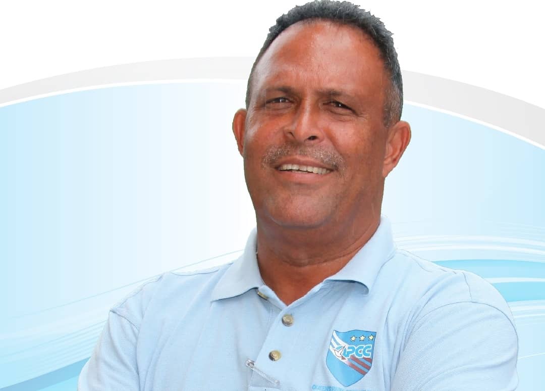 David Furlonge, a smiling middle-aged man, wears a light blue polo shirt with a Queen’s Park Cricket Club logo.