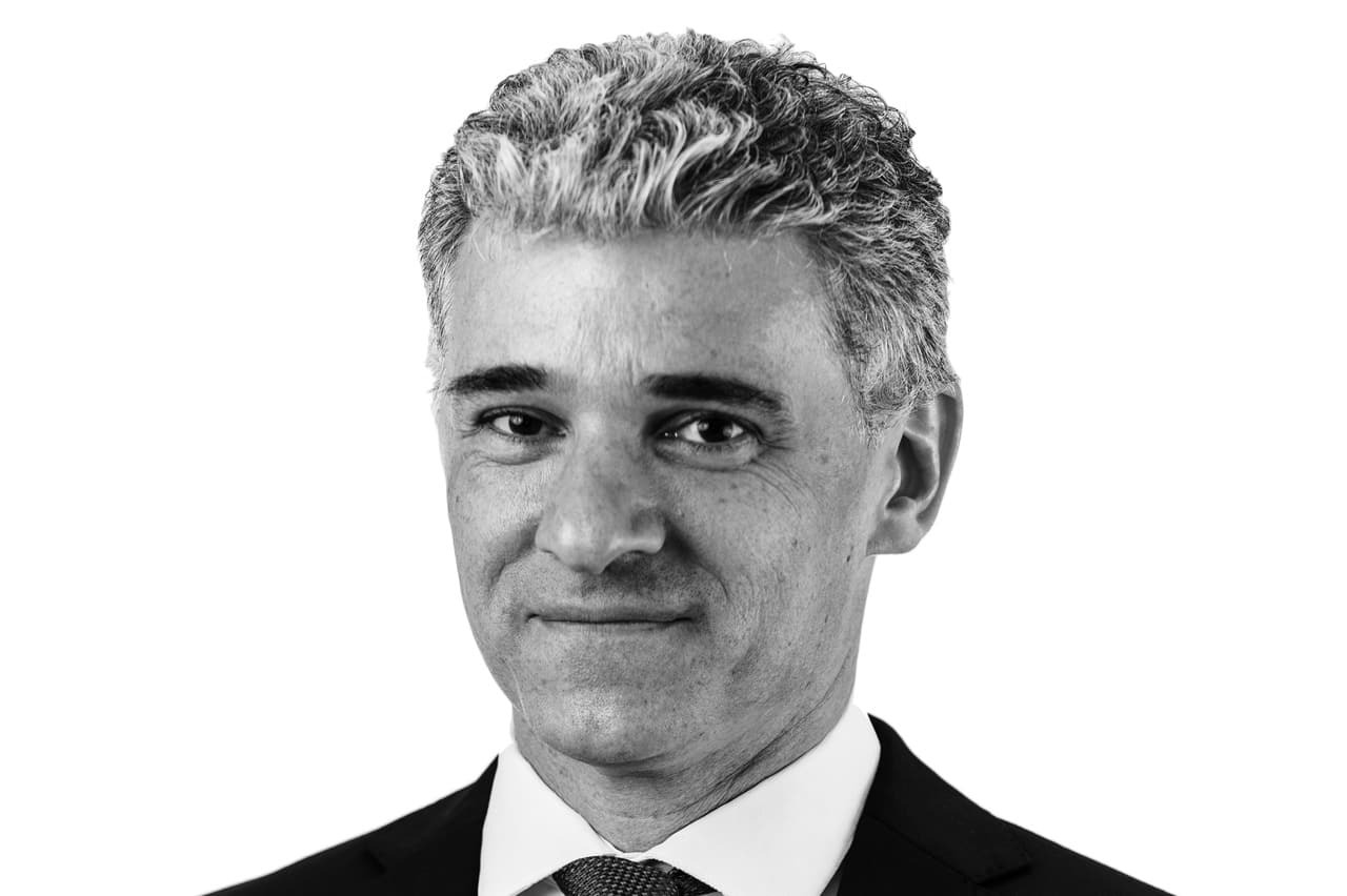 A black-and-white portrait of Thackwray Dax Driver in a suit and tie.
