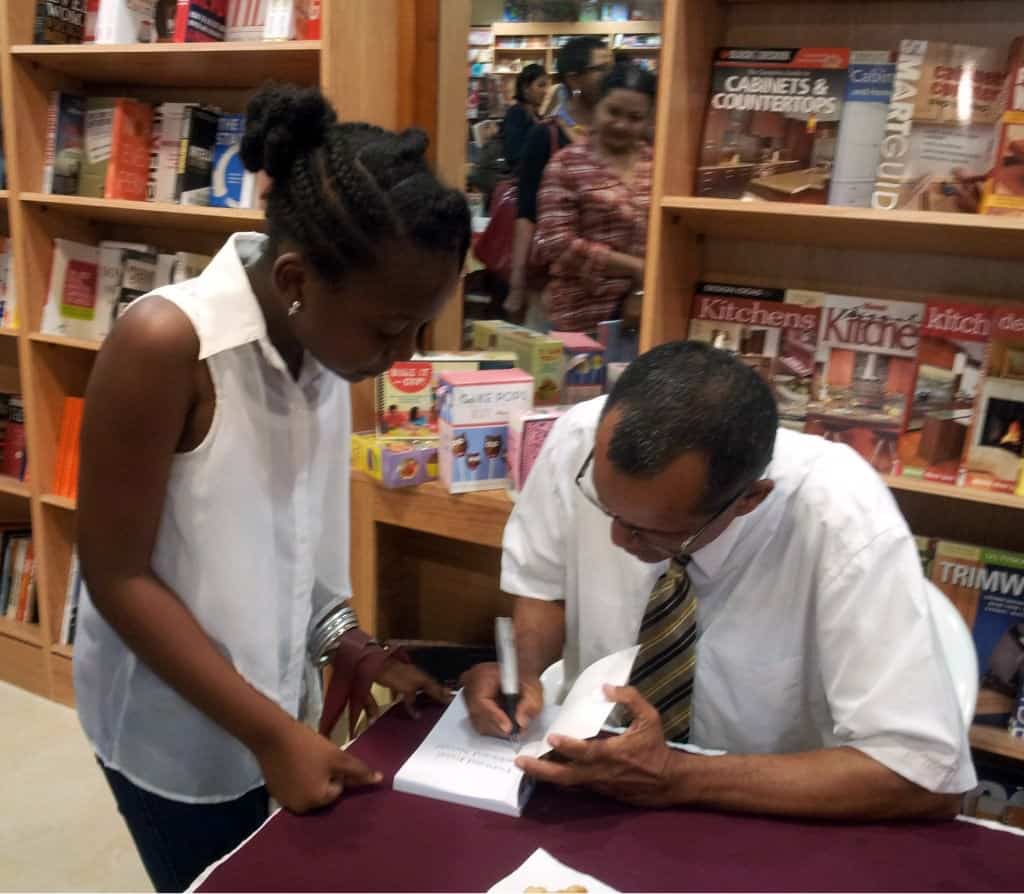 Author Michael Cozier autographs his book for a young fan, following his reading.