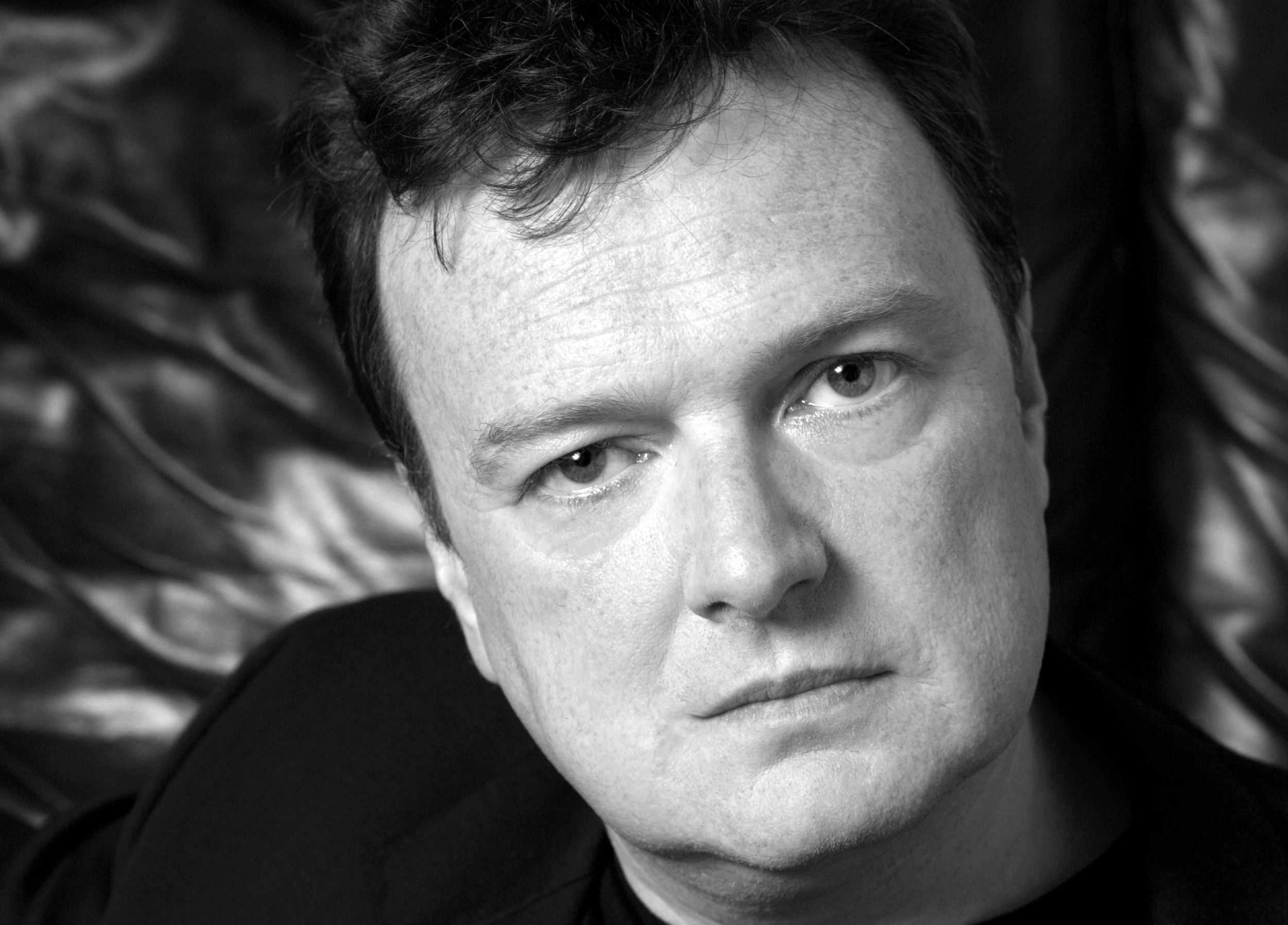 Black and white headshot of a middle-aged man with dark hair looking directly at the camera.