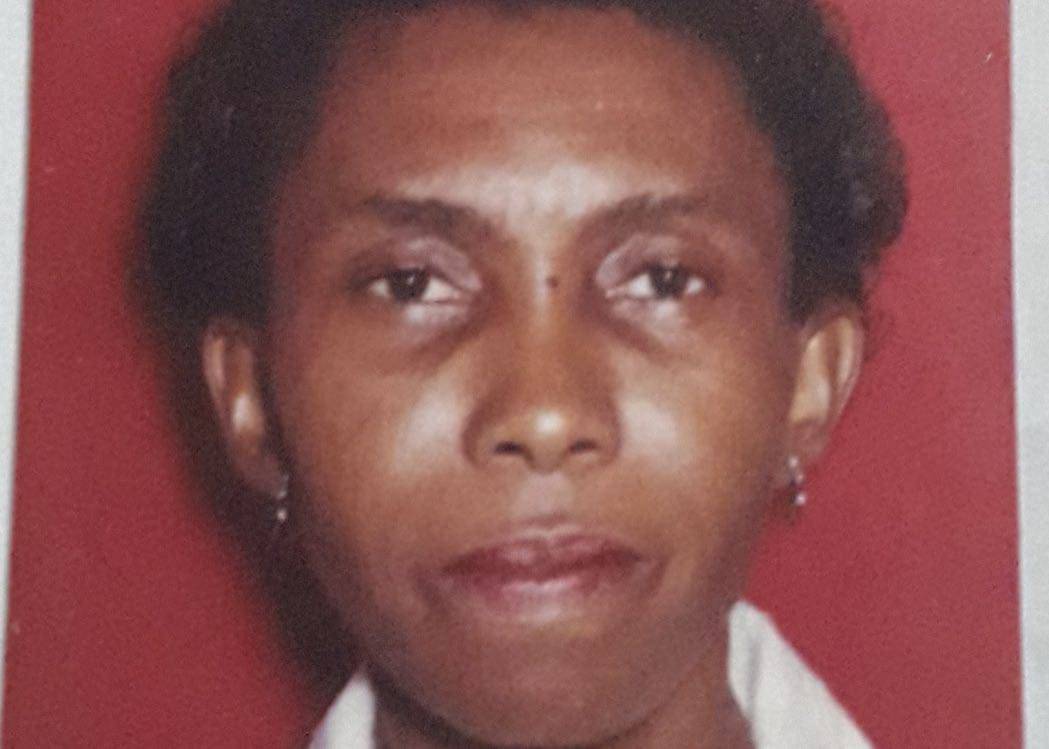 Passport-style headshot of Jennifer Thomas-Straker, a woman with dark skin and short dark hair against a red background.