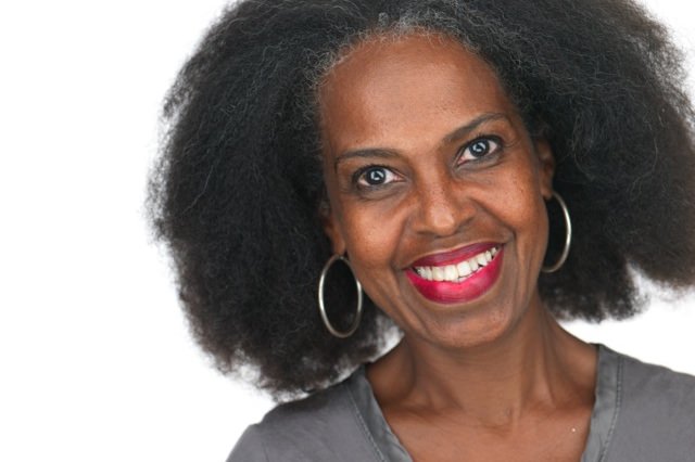 Headshot of Malaika Adero, a smiling woman in the publishing business with voluminous dark hair and silver hoop earrings.