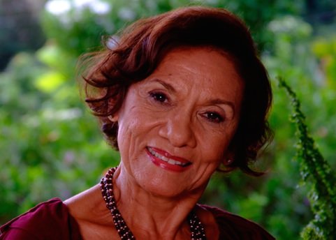 A smiling woman with shoulder-length dark hair wearing a beaded necklace, as seen in the Brown Sugar & Spice cookery book by Betty Peter.
