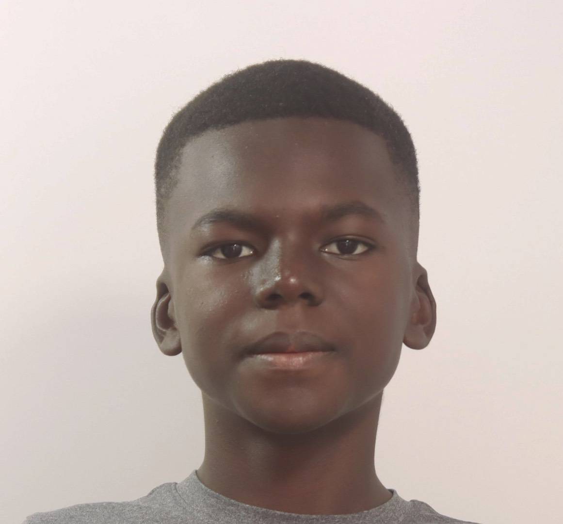 Portrait of a young Black boy looking at the camera against a light background.